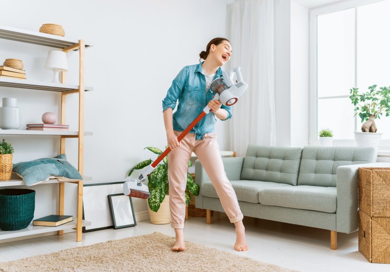 Frau reinigt glücklich ihre Wohnung mit einem Stausauger mit Wischfunktion