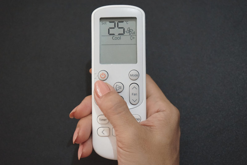 Eine mobile Klimaanlage wird per Fernbedienung gesteuert. Es sind verschiedene Einstellungen sichtbar. 